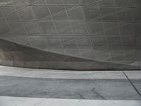 a person walking through a courtyard with an umbrella on the floor by a wall and curved roof