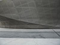a person walking through a courtyard with an umbrella on the floor by a wall and curved roof