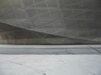 a person walking through a courtyard with an umbrella on the floor by a wall and curved roof