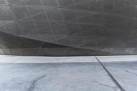 a person walking through a courtyard with an umbrella on the floor by a wall and curved roof