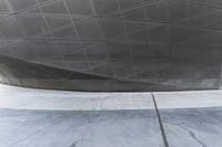 a person walking through a courtyard with an umbrella on the floor by a wall and curved roof