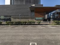 a building with two parking spaces on the lot in front of it, and an entrance sign, next to a sign saying international education