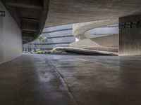 concrete is in the room with stairs and a large white building behind it that has curved windows, a walkway with steps, and an indoor swimming pool