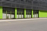 a green and black building sitting on the side of a road next to a yellow fire hydrant