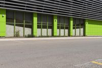 a green and black building sitting on the side of a road next to a yellow fire hydrant