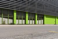 a green and black building sitting on the side of a road next to a yellow fire hydrant