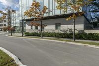 a red stop sign is in front of a modern building with a concrete curb with grass and trees around it