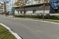 a red stop sign is in front of a modern building with a concrete curb with grass and trees around it