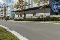 a red stop sign is in front of a modern building with a concrete curb with grass and trees around it