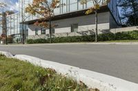 a red stop sign is in front of a modern building with a concrete curb with grass and trees around it