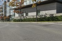 a red stop sign is in front of a modern building with a concrete curb with grass and trees around it