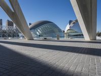 there is a very modern building that sits next to the water and a big city