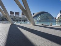 there is a very modern building that sits next to the water and a big city