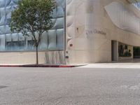 a fire hydrant on the corner of a street in front of the glass building