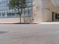 a fire hydrant on the corner of a street in front of the glass building