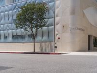 a fire hydrant on the corner of a street in front of the glass building