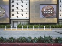 an area with a few parking meters of plants on it and two ads in the background
