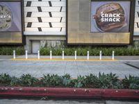 an area with a few parking meters of plants on it and two ads in the background