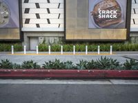 an area with a few parking meters of plants on it and two ads in the background