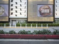 an area with a few parking meters of plants on it and two ads in the background