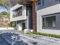 the exterior and landscape of a modern house in los angeles, california with stone and wood