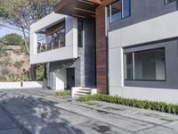 the exterior and landscape of a modern house in los angeles, california with stone and wood