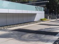 a concrete sidewalk with the letters 001 on it and trees behind it next to a wall