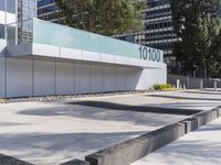 a concrete sidewalk with the letters 001 on it and trees behind it next to a wall