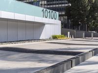 a concrete sidewalk with the letters 001 on it and trees behind it next to a wall