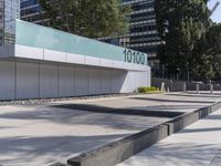 a concrete sidewalk with the letters 001 on it and trees behind it next to a wall