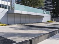 a concrete sidewalk with the letters 001 on it and trees behind it next to a wall