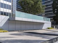 a concrete sidewalk with the letters 001 on it and trees behind it next to a wall