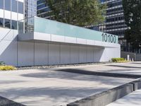 a concrete sidewalk with the letters 001 on it and trees behind it next to a wall