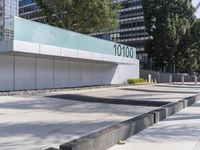 a concrete sidewalk with the letters 001 on it and trees behind it next to a wall