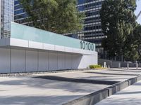 a concrete sidewalk with the letters 001 on it and trees behind it next to a wall