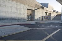 a skateboard parked in a parking lot at an arena with concrete walls and stairs