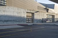 a skateboard parked in a parking lot at an arena with concrete walls and stairs