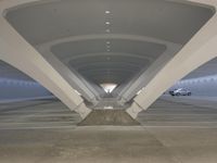 this photo shows a concrete parking space underneath an overpass area with a row of columns