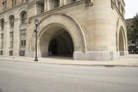 an old arched building is shown with a car parked under the entrance at the end of it