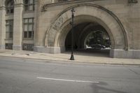an old arched building is shown with a car parked under the entrance at the end of it