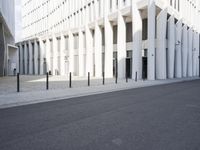 an empty street with a lot of poles by it and a building in the background