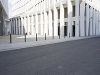 an empty street with a lot of poles by it and a building in the background