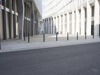 an empty street with a lot of poles by it and a building in the background