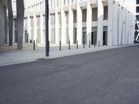 an empty street with a lot of poles by it and a building in the background