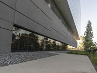 the building is very long and large outside of it's windows the reflection in the glass reflects the landscape