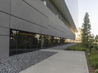 the building is very long and large outside of it's windows the reflection in the glass reflects the landscape