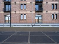 the bicycle is parked in front of a brick building with lots of windows and doors