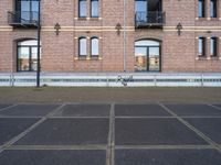 the bicycle is parked in front of a brick building with lots of windows and doors