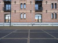 the bicycle is parked in front of a brick building with lots of windows and doors