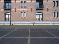 the bicycle is parked in front of a brick building with lots of windows and doors